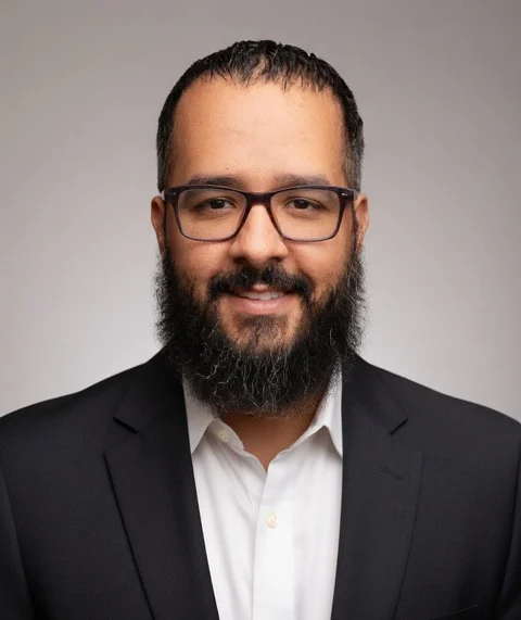 Kris Cruz, ordained Texas chaplain in a black suit and glasses