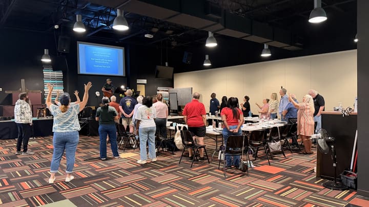 Ministry team standing in worship with hands raised in a North Texas gathering hall